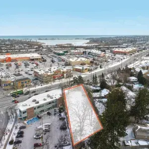 Aerial of site, outlined in orange, from the rear, showing retail stores in the area