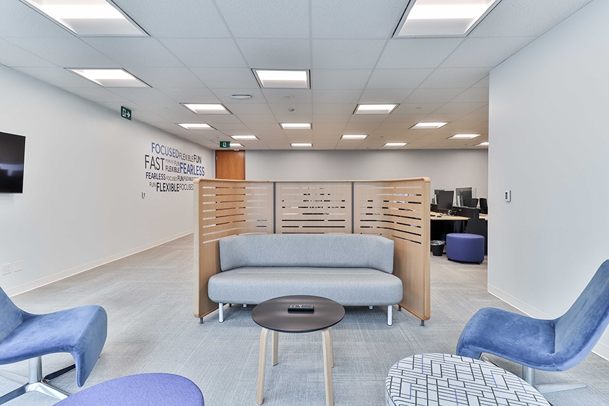 181 Bay Street Common area with blue and grey sofa and stools facing the open office are