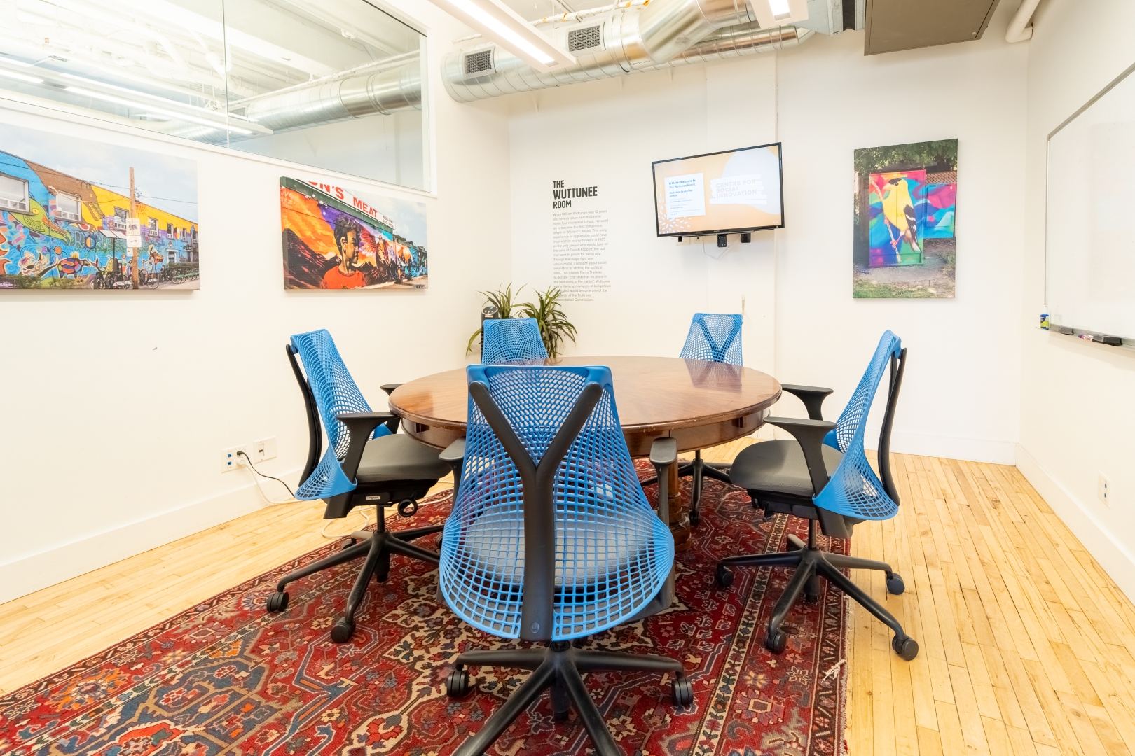 192 Spadina Avenue Fourth Floor bookable meeting room with paintings on the wall and round meeting table