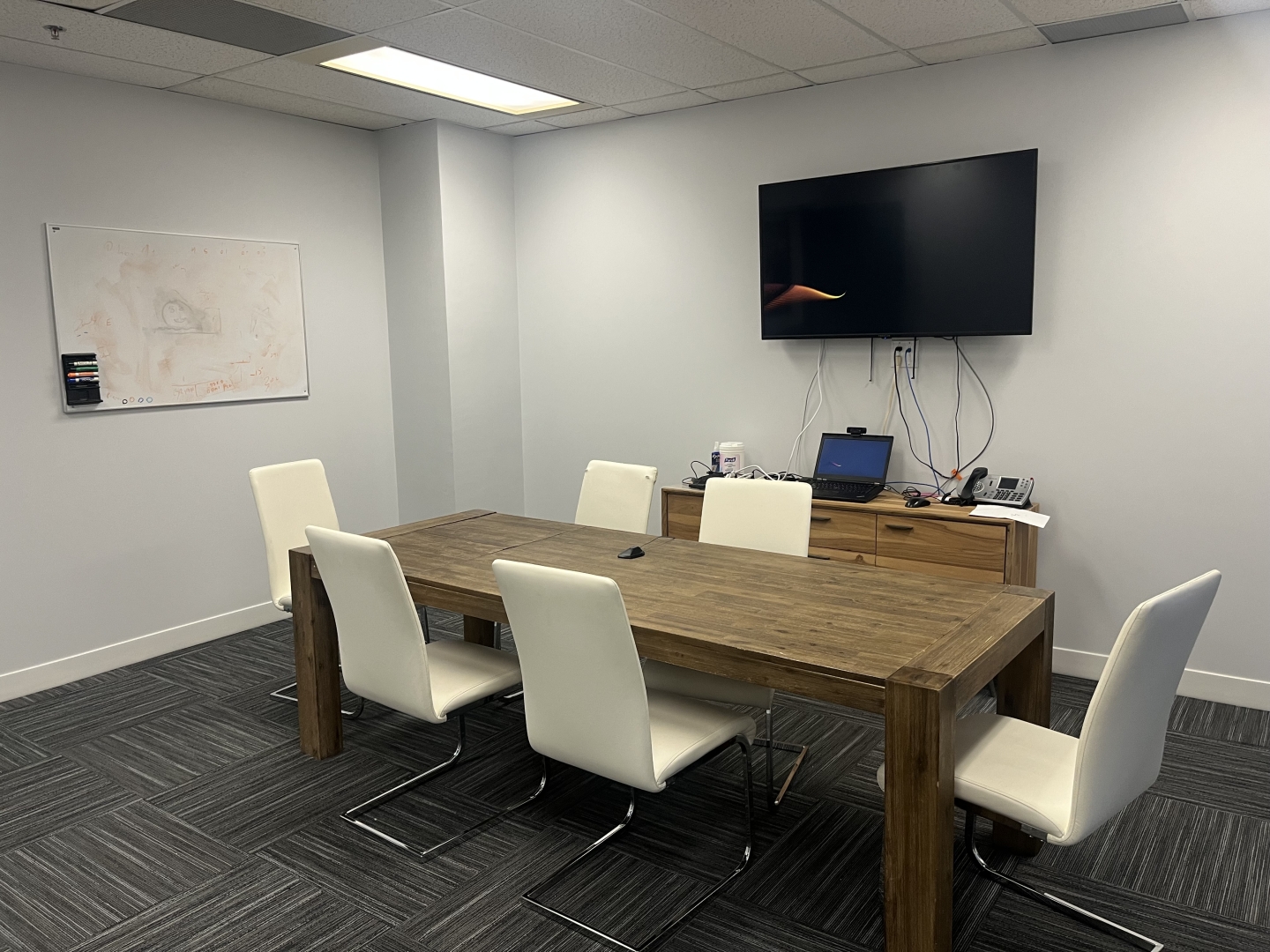 184 Front Street E meeting room with a TV overlooking a desk and some white chairs