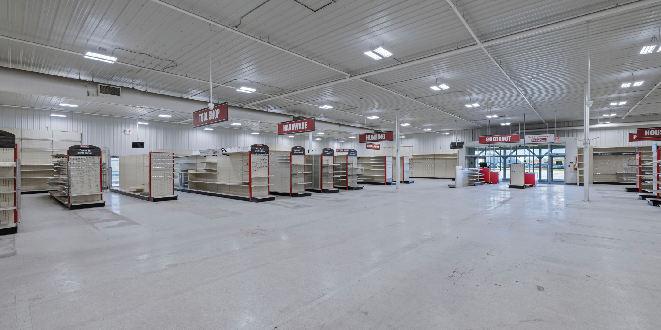 Interior of empty former Peavey Mart store, looking to glass door outside