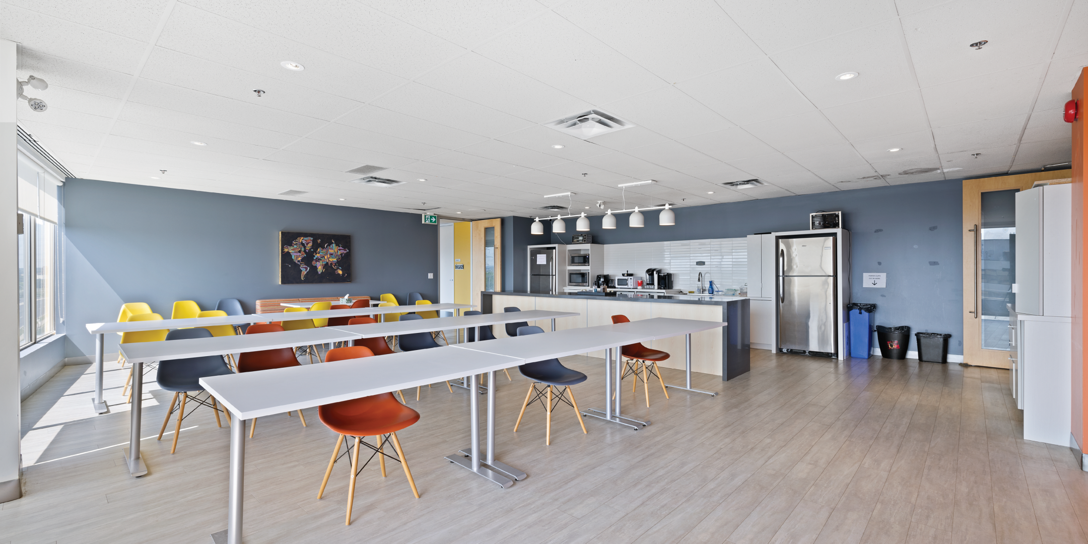 office building kitchen area with wood flooring, island and table seating