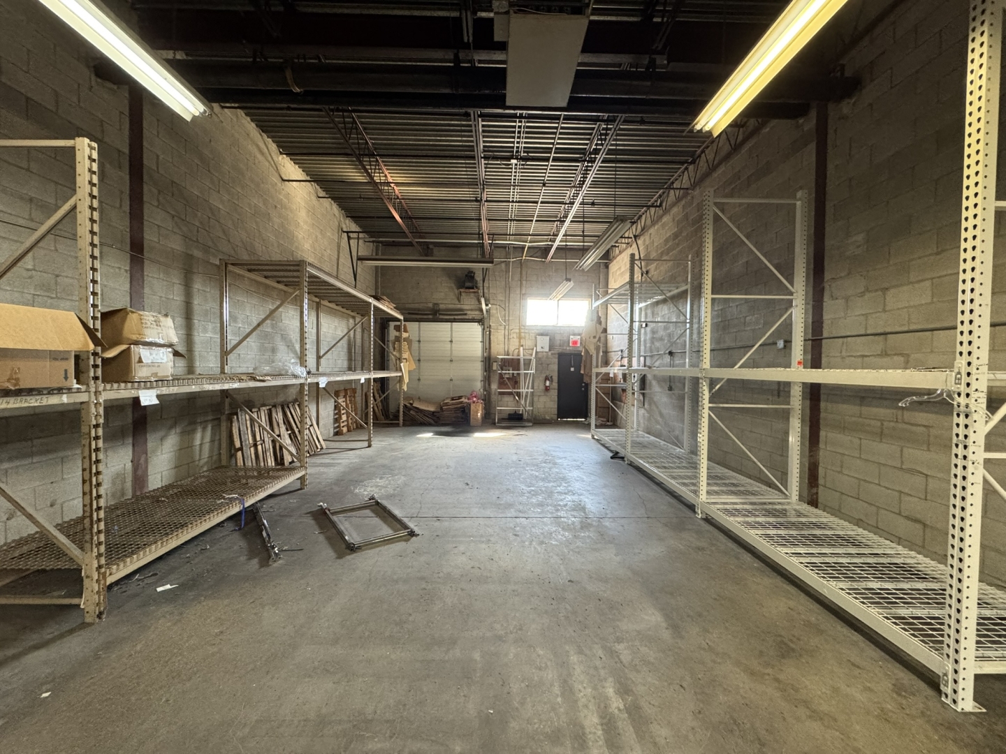 225 Nugget Avenue interior warehouse with concrete floors, one window, one shipping door and shelving along walls 