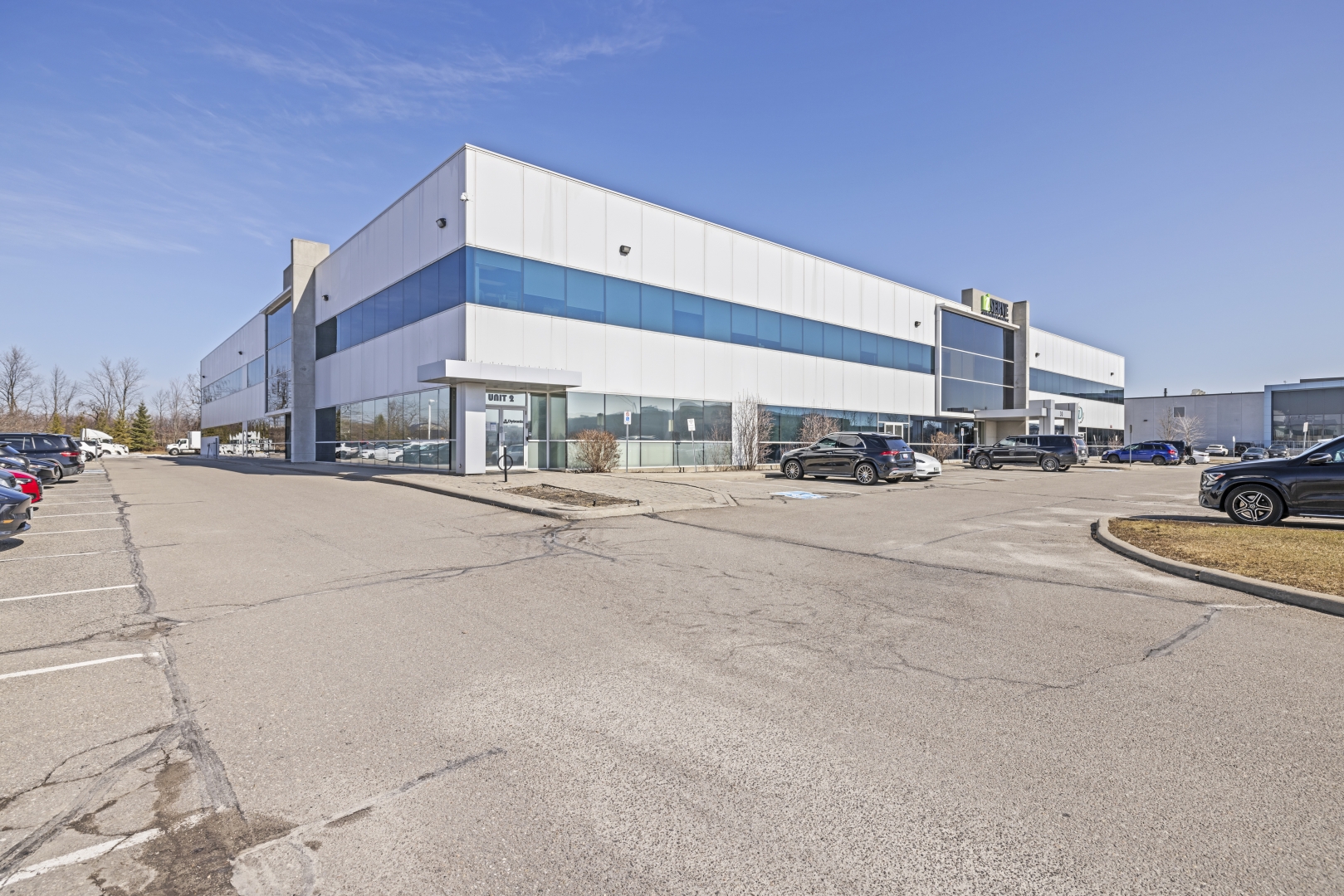 30 Via Renzo Drive front view of two storey white building with large windows and front entrance and lots of front parking 