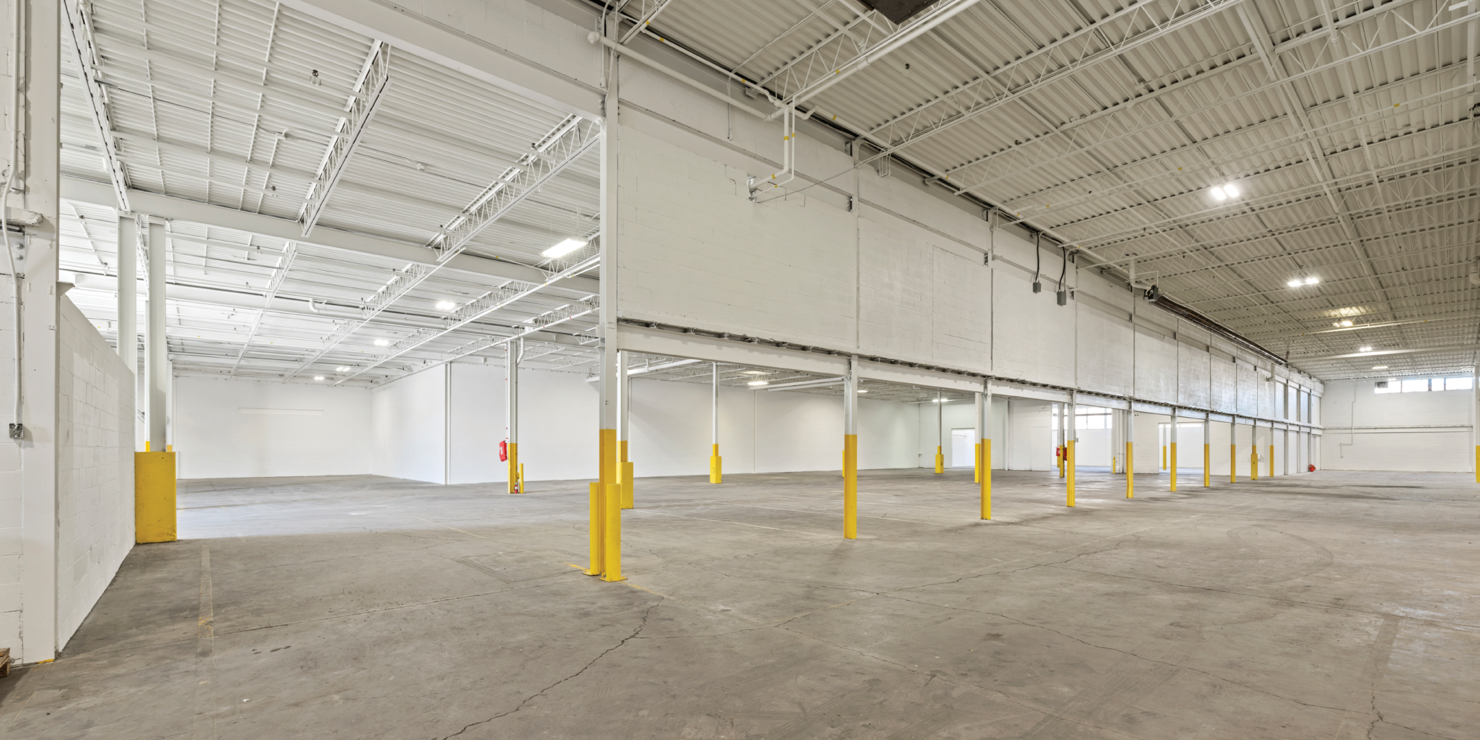 3636 Weston Road interior empty warehouse with concrete floors and painted white walls, half wall from ceiling through middle of warehouse
