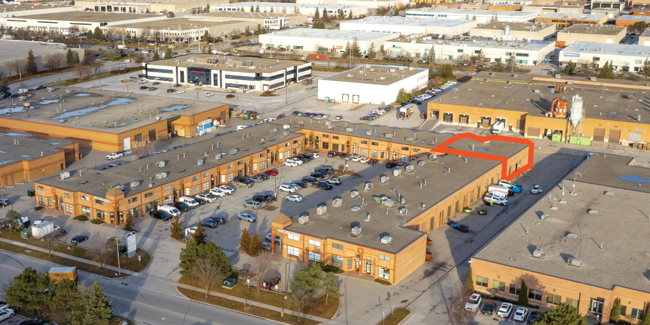 Aerial of red brick industrial complex with available unit outlined in orange