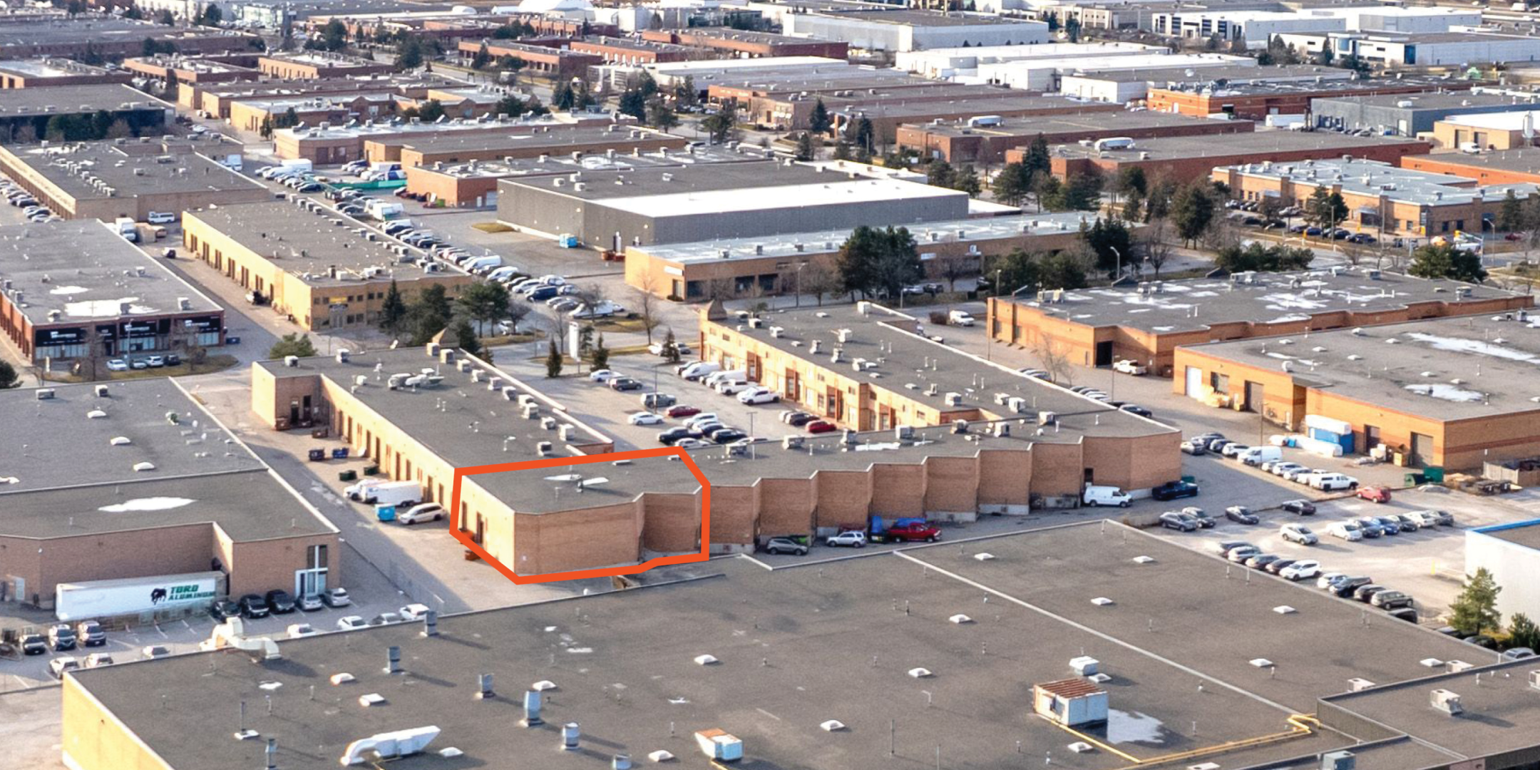 Aerial of back of red brick industrial complex with available unit outlined in orange