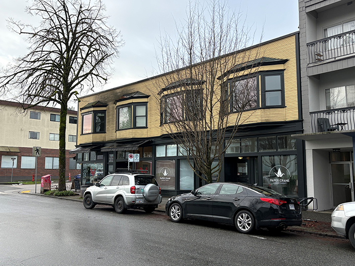 2 storey mixed use commercial and residential building with yellow siding and grey accents