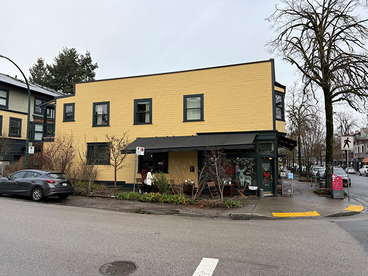 side of 2 storey mixed use commercial and residential building with yellow siding and grey accents