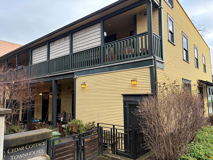 rear of 2 storey mixed use commercial and residential building with yellow siding and grey accents