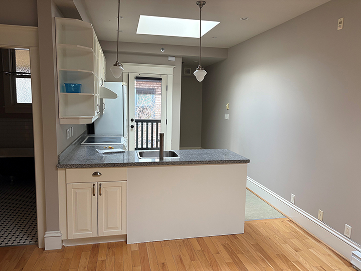 kitchen area with prep area and sink, light hardwood flooring and grey walls