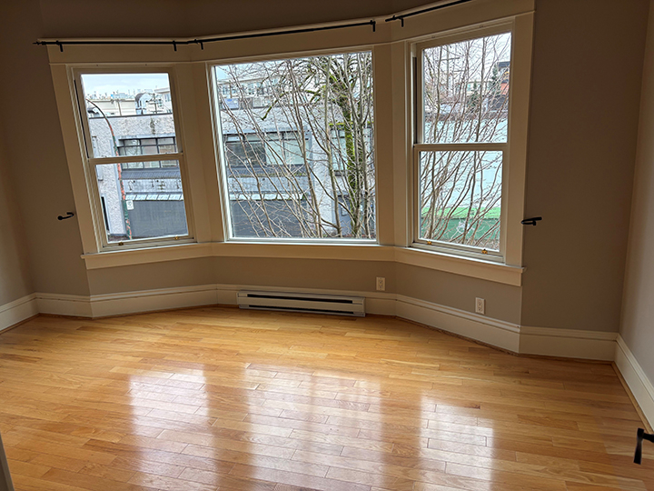 empty living area with shiny light hardwood floors and bay window