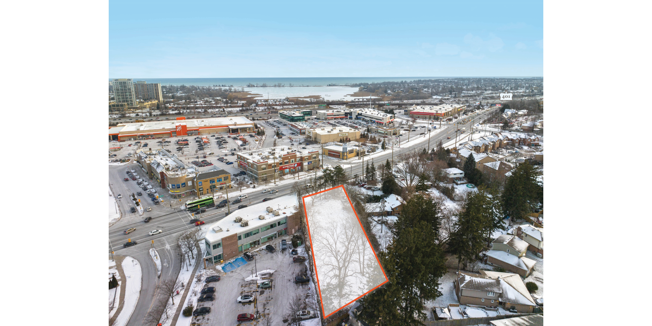 Aerial of site, outlined in orange, from the rear, showing retail stores in the area