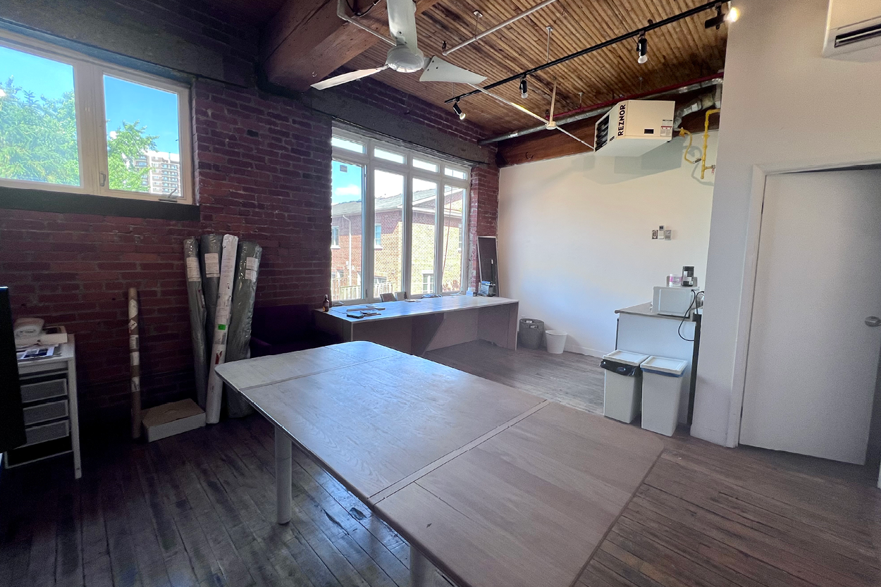 77 Florence Street bright office suite with large windows, exposed brick wall, and wooden ceiling.