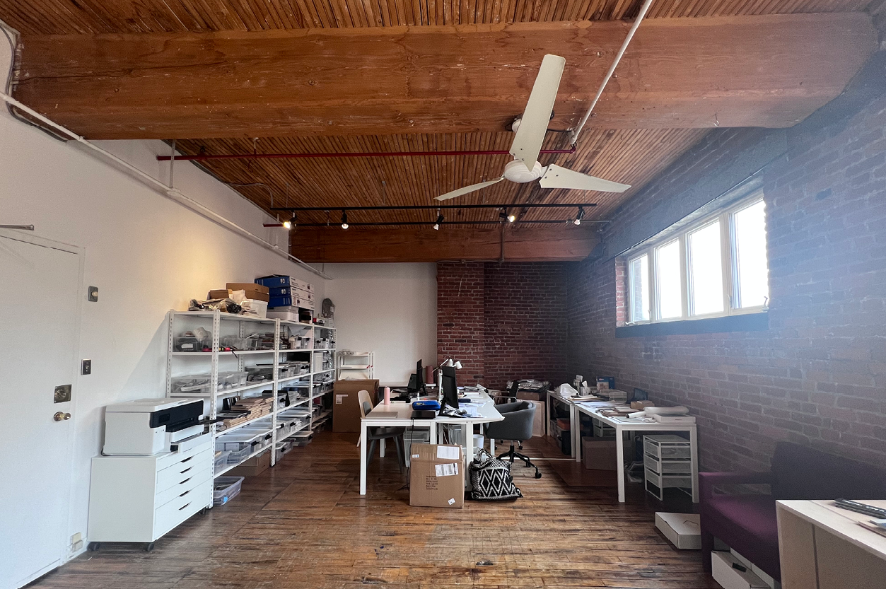 77 Florence Street open office area with desks, shelving units, and hardwood flooring.
