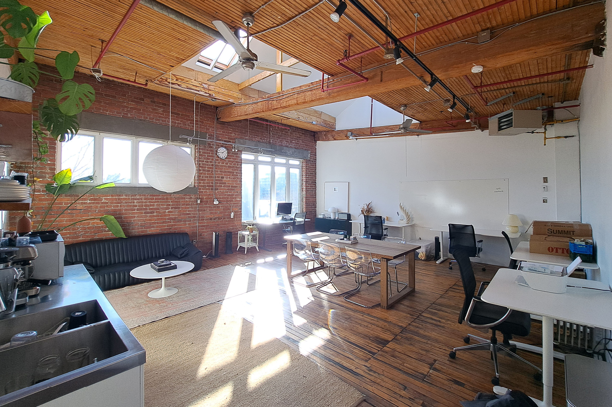 77 Florence Street wide open workspace with skylights, wooden beams, and collaborative desk area.