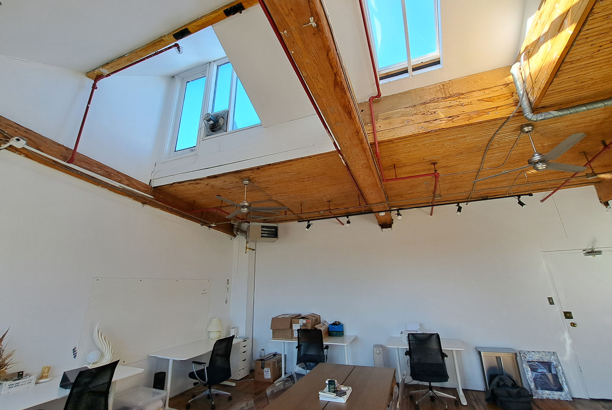 77 Florence Street high ceiling office interior with exposed beams, skylights, and workstations.