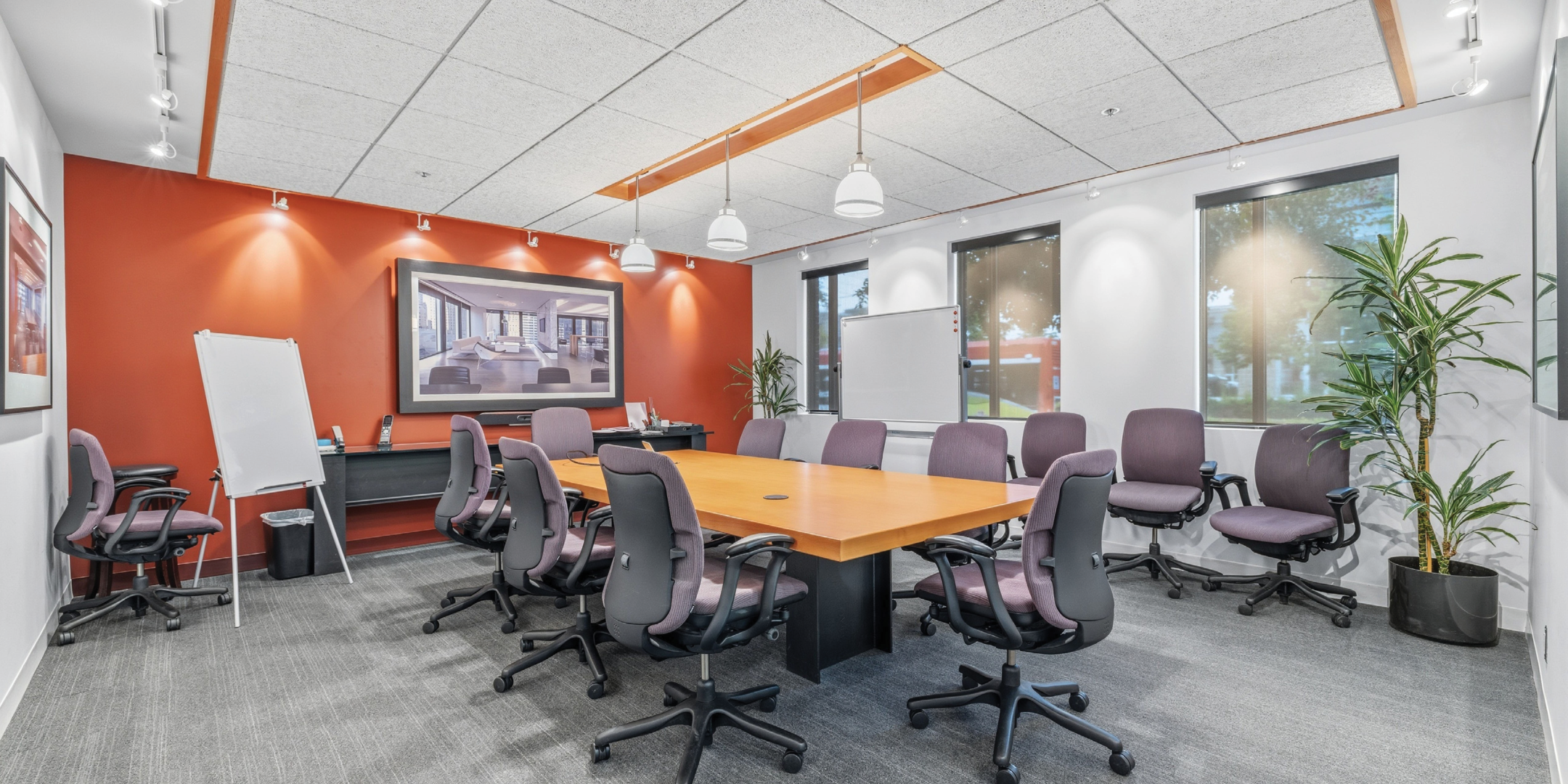 boardroom with orange accent wall, bright lighting, grey tile flooring
