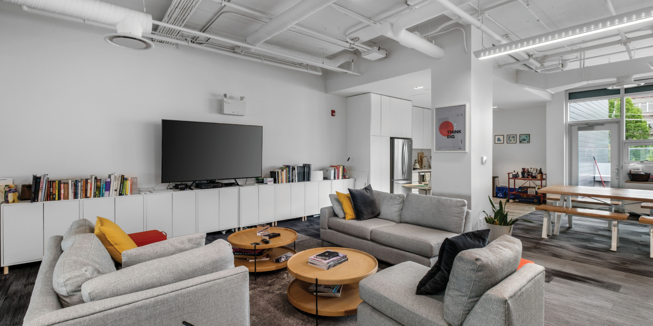 Office lounge area next to kitchen with sectionals and TV