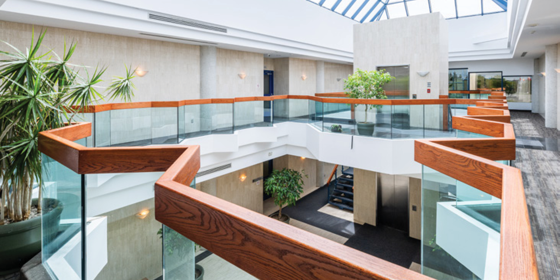 Second floor view of Atrium of 2 storey office building with cream walls, skylight