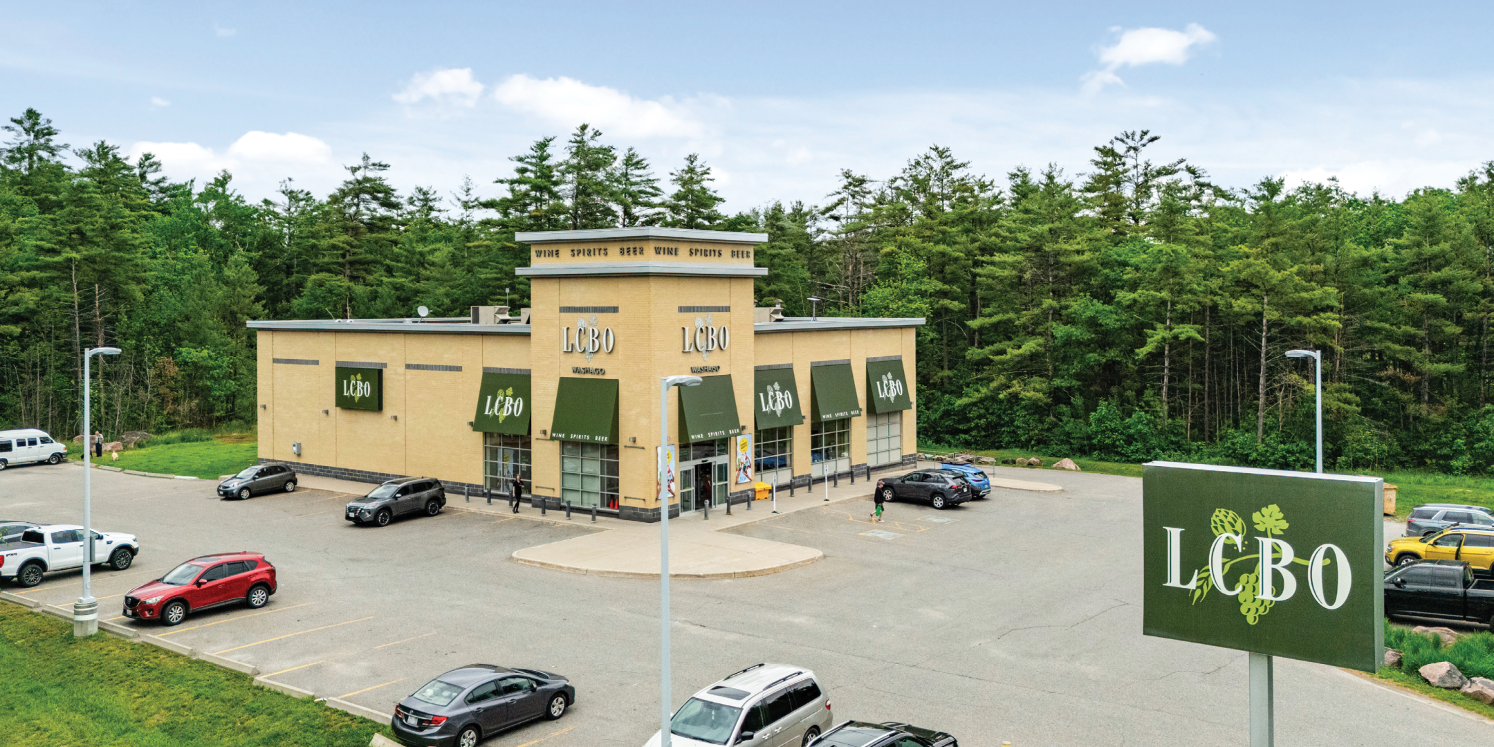 Drone photo of standalone LCBO building with yellow facade and green awnings