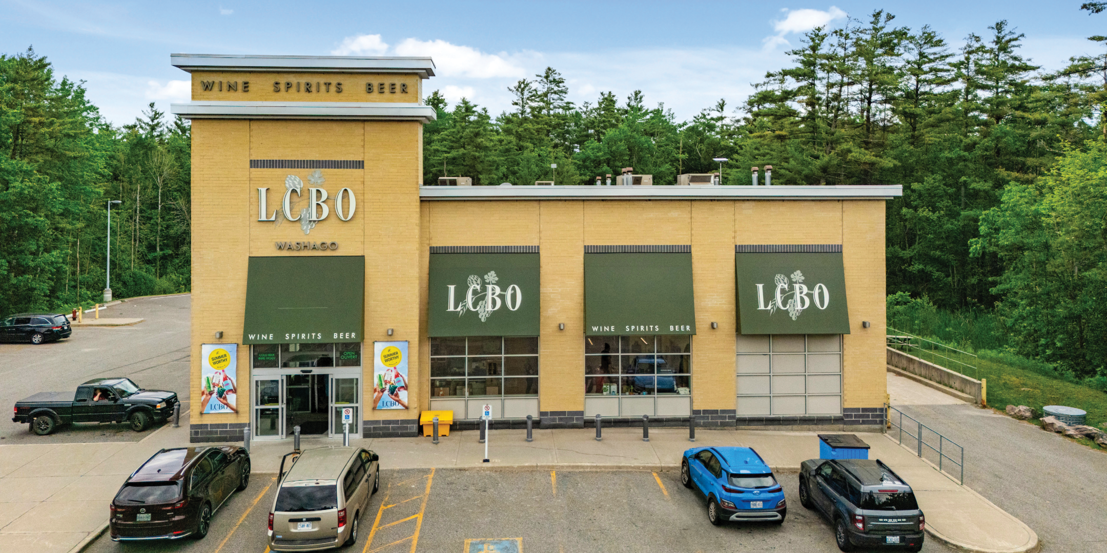 Front of standalone LCBO building with yellow brick and green awning