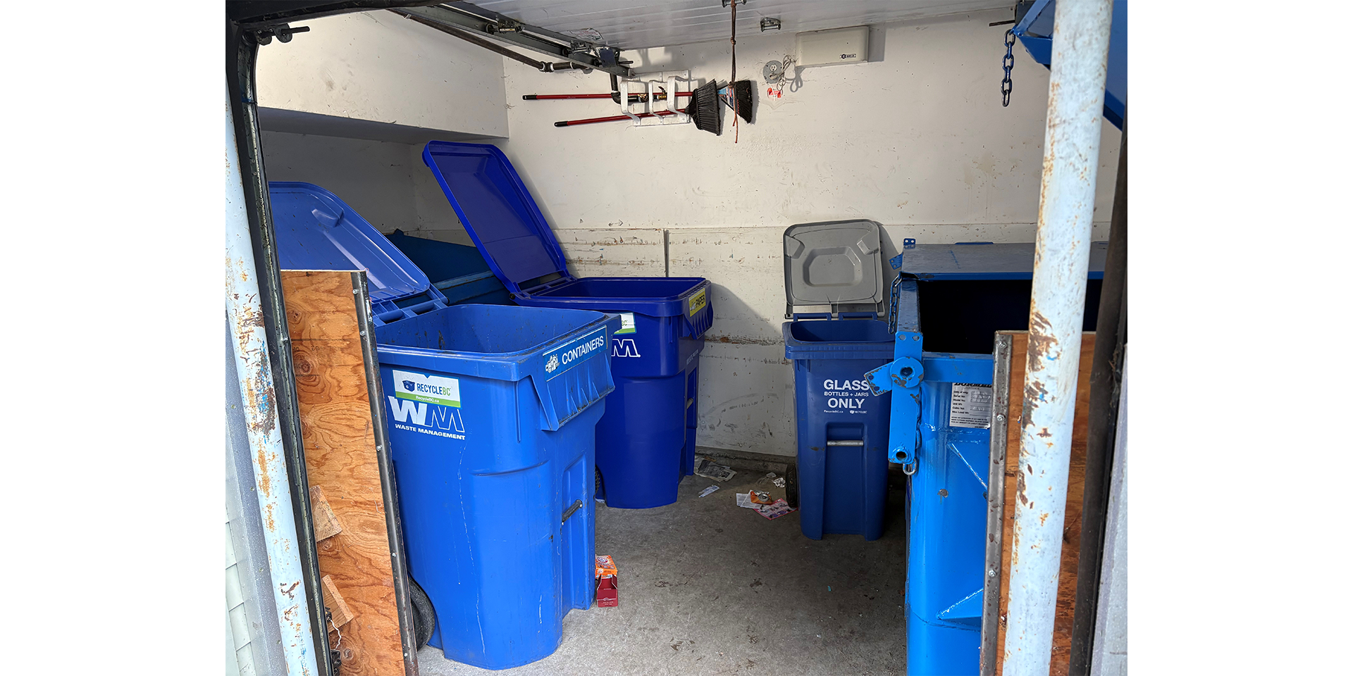 Room with garbage bins, recycling bins, and a dumpster