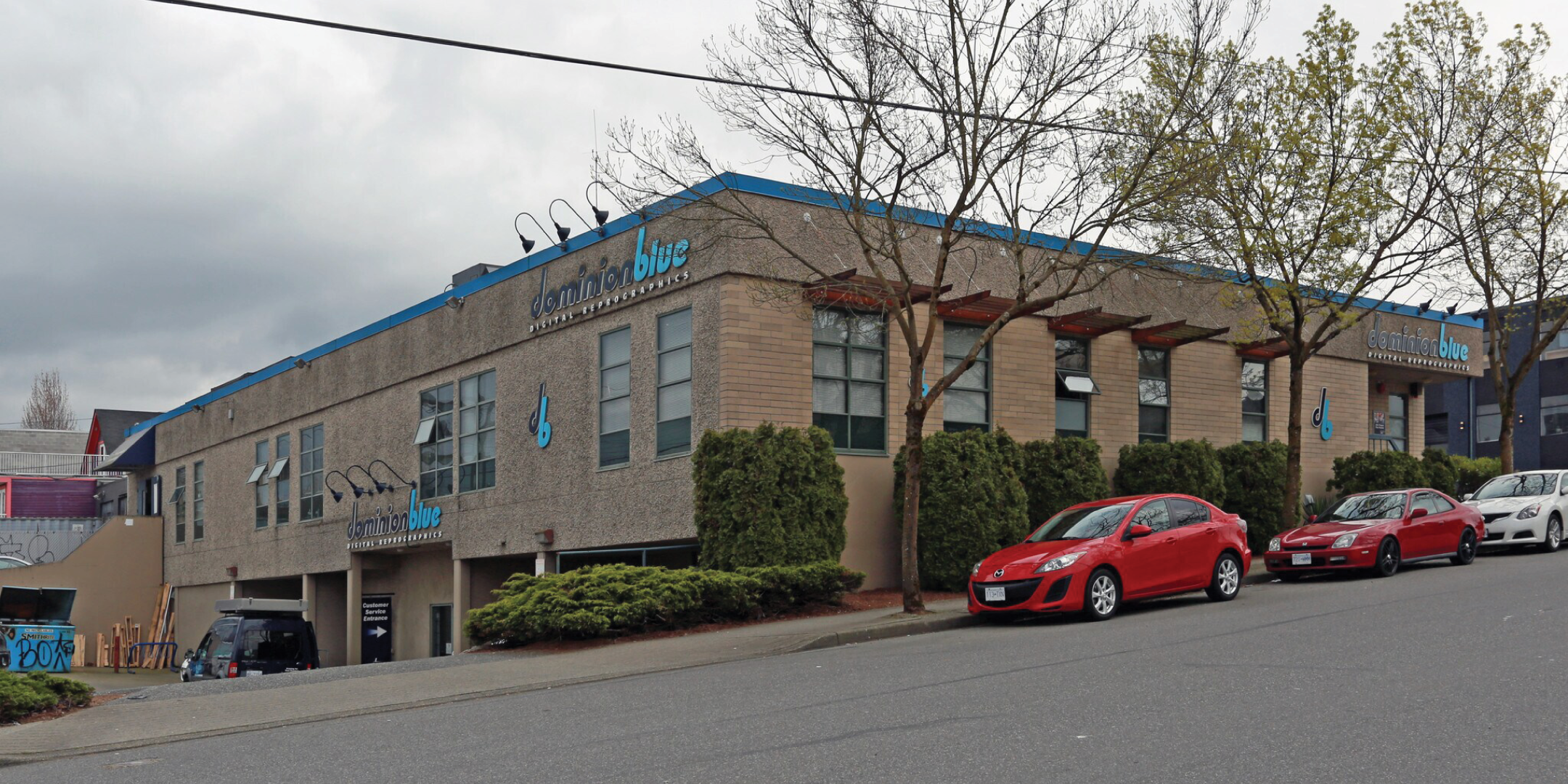 99 West 6th Avenue building exterior showing side street, parking, and rear door
