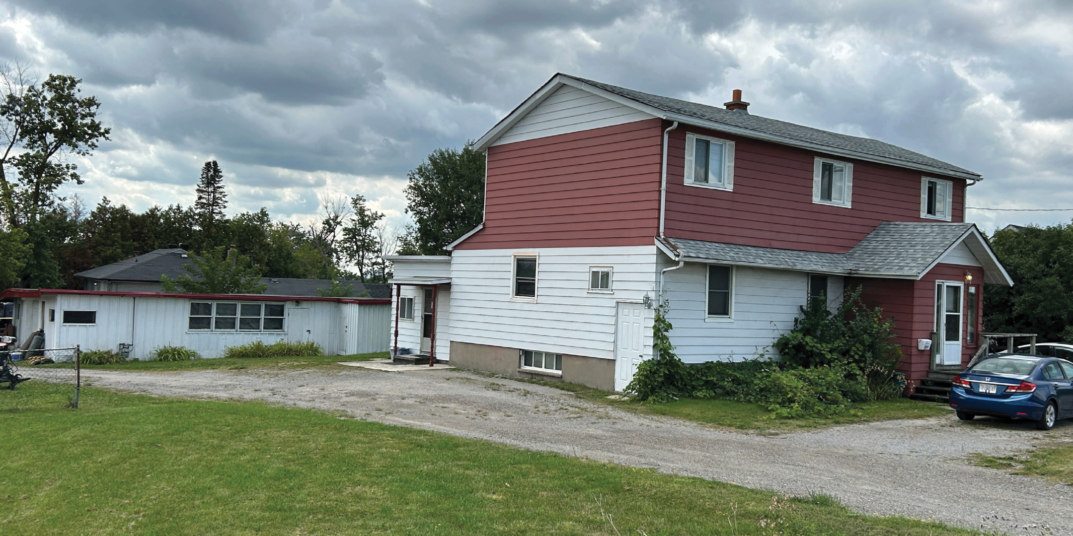 2 level house with red and white siding and workshop/garage on left side rear of property