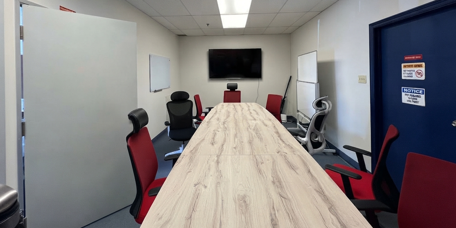 455 Cochrane Drive 24-25 meeting room showing a long table, red chairs, and tv in the middle