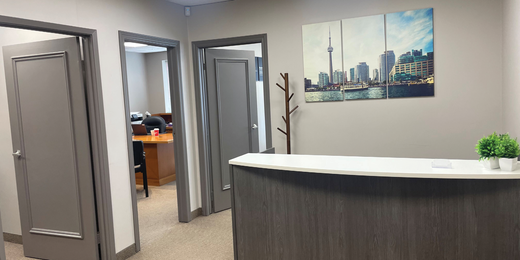 reception area with desk and showing doors to 3 private offices